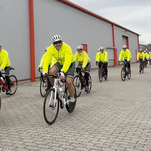 Radfahrer in gelben Regenjacken bei der Einfahrt auf einem gepflasterten Hof